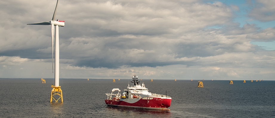 A photo of Subsea 7 vessel next to a wind turbine at sea